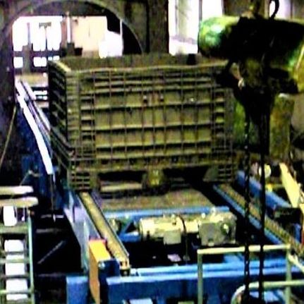 Bulk material bin riding on twin chain strands of a chain conveyor inside a plant