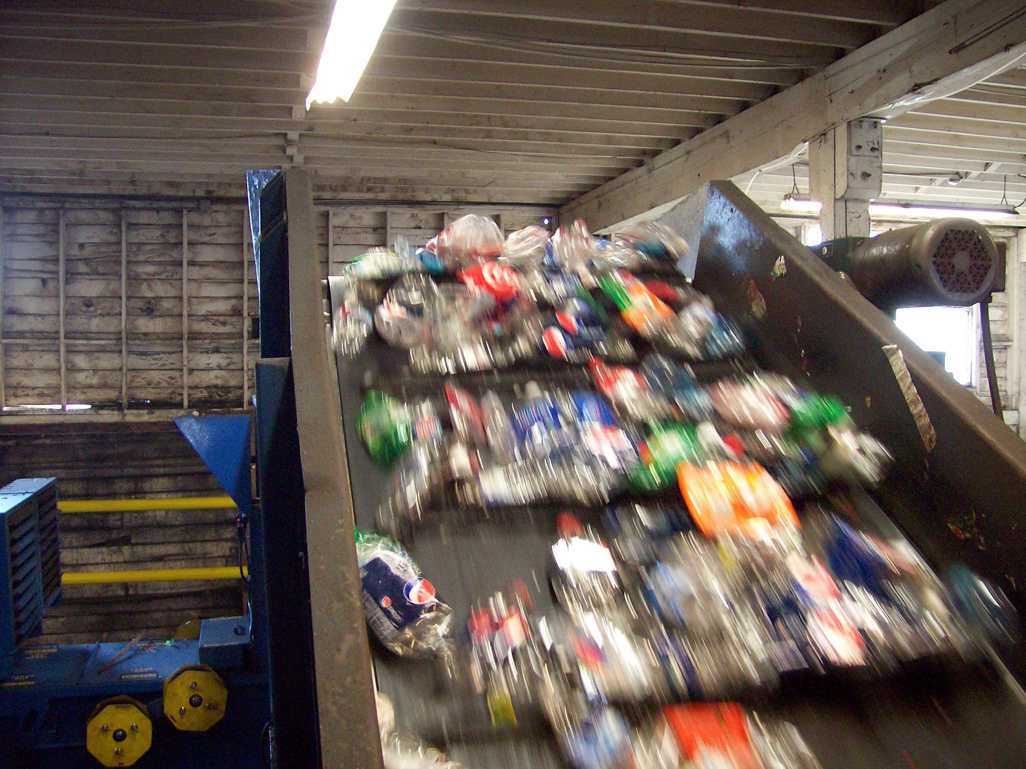 Commingled recyclables riding up an incline conveyor inside a working recycling plant