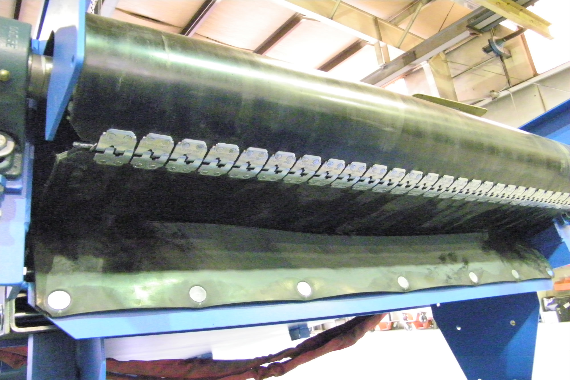 Mechanical belt lacing at the head pulley of a rubber belt conveyor, seen from below