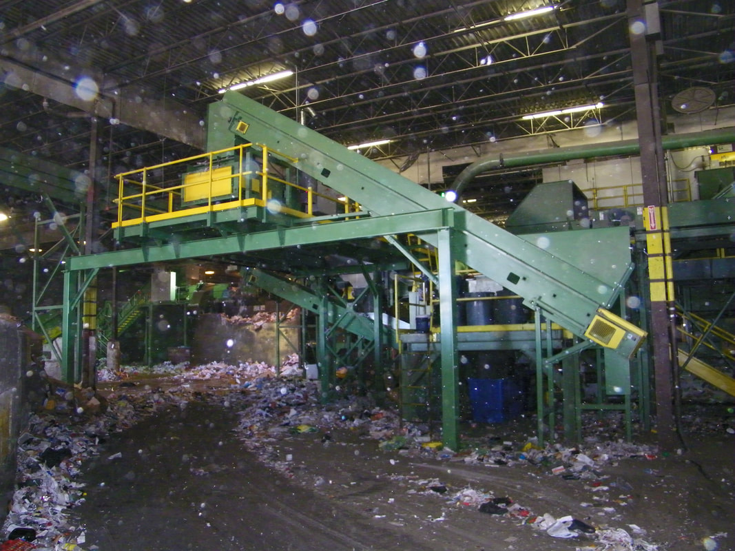 Incline feed conveyor to optical sorter on a custom support platform with drive-thru access below