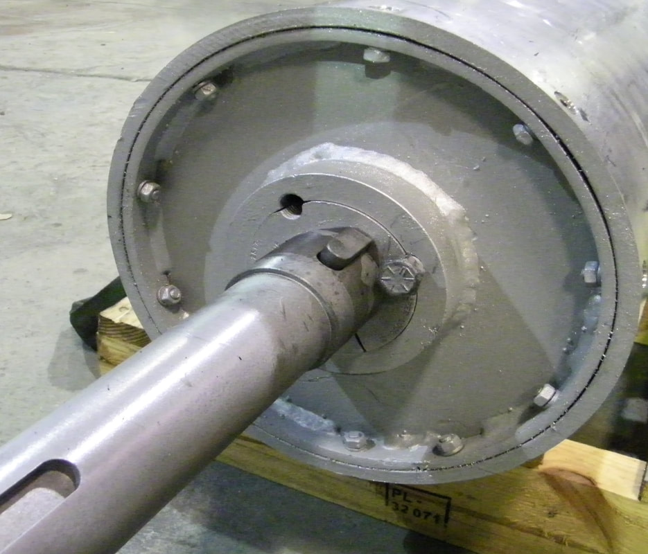 Magnetic head pulley with keyed drive shaft on a shipping pallet, showing the bolted replaceable outer shell