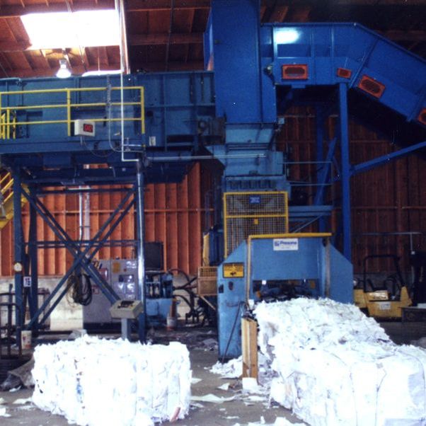 Drag chain belt baler feed conveyor discharging into a baler