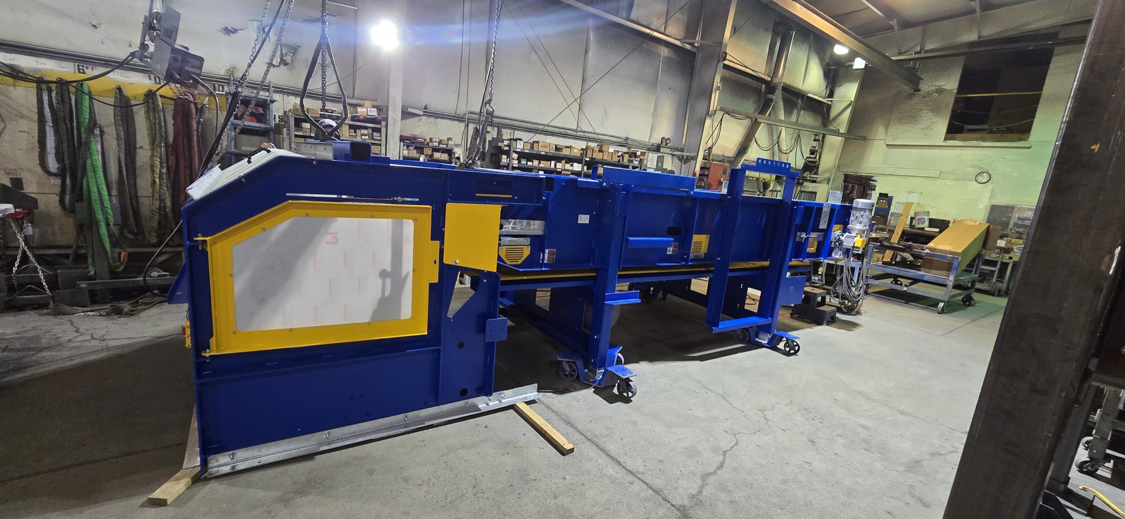 Remcon slider bed conveyor with a custom yellow-framed inspection hood, freshly finished in the shop