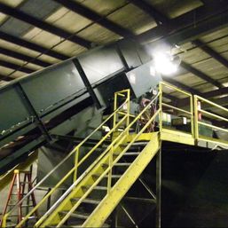 Incline feed conveyor carrying material up to a sort line