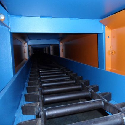 Two parallel strands of chain connected by steel cross members inside an enclosed conveyor frame
