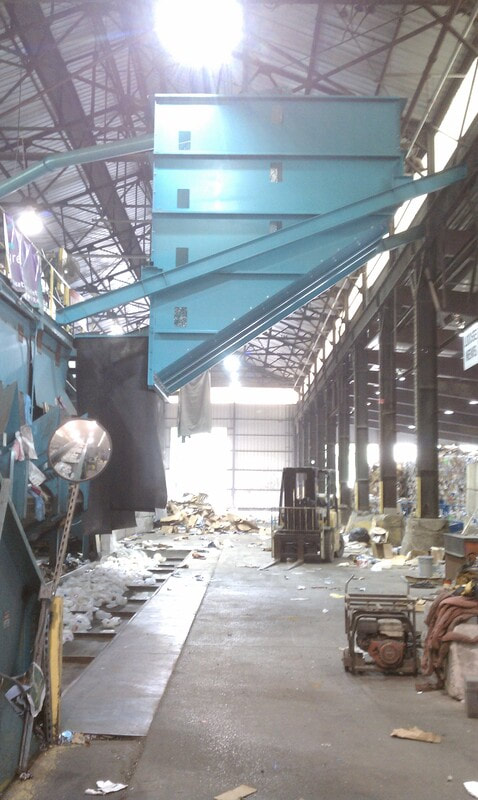 Elevated storage silo fed by a blower tube, discharging over a baler feed conveyor